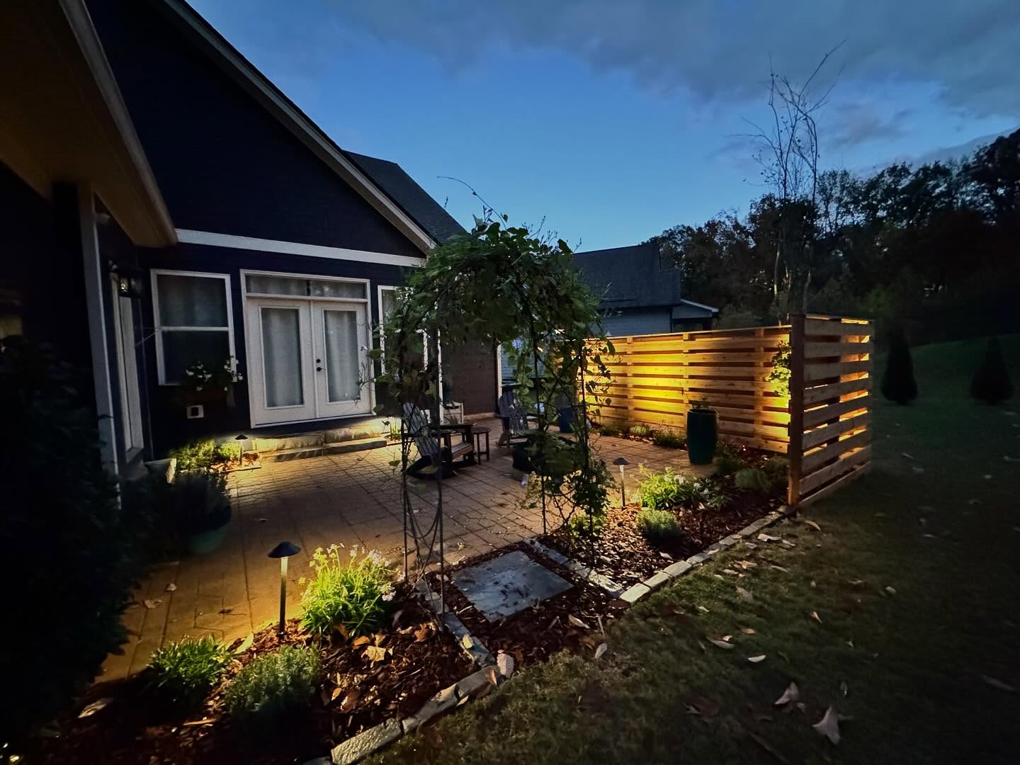 Back patio with flower beds, privacy wall and accent lighting
