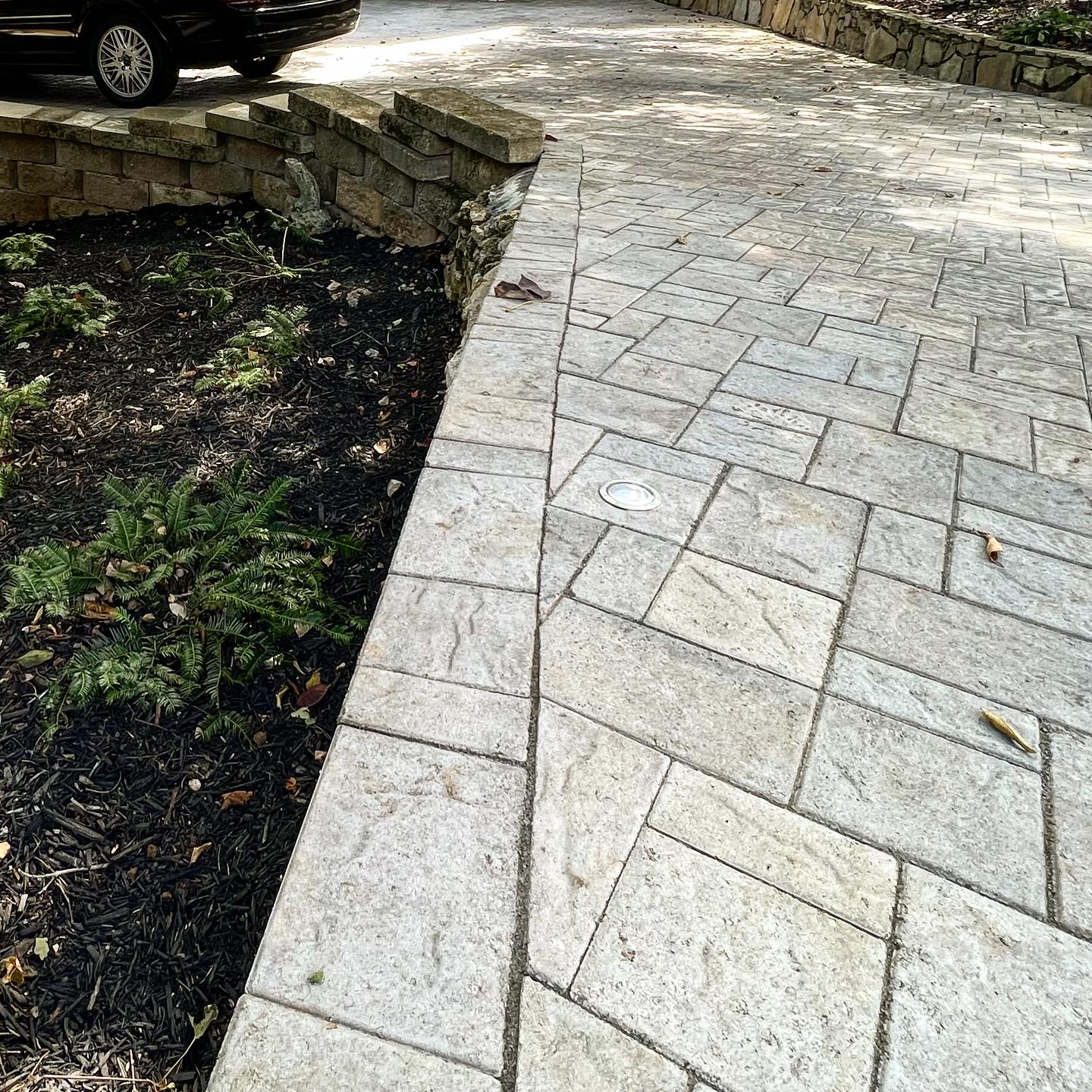 Geometric paver driveway design with inset landscape lighting